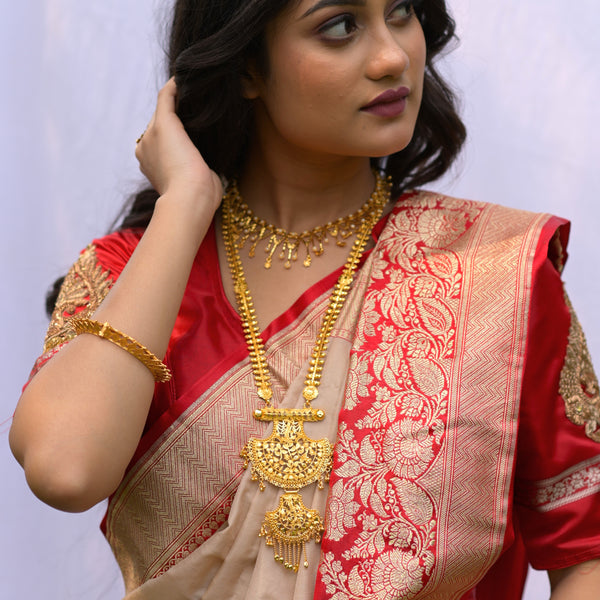 Model wearing a traditional Bengali gold plated jewelry set with necklace and earrings, complemented by a red saree.