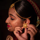 Bengali woman showcasing traditional gold plated earrings with intricate detailing and makeup.