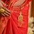Kumud Komor Jhapta gold plated accessory, detailed close-up on red saree, stylish accent for traditional wear.