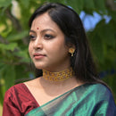 Beautiful woman wearing a gold plated floral choker necklace and matching earrings, showcasing elegant jewelry design.