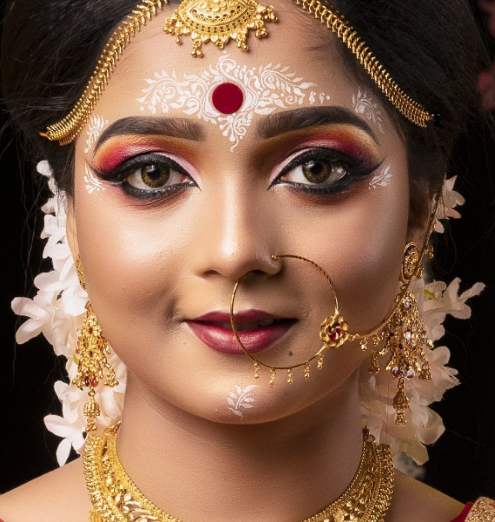 Pretty and attractive Indian woman with traditional bridal attire fixing  her nose piercing Stock Photo by wirestock